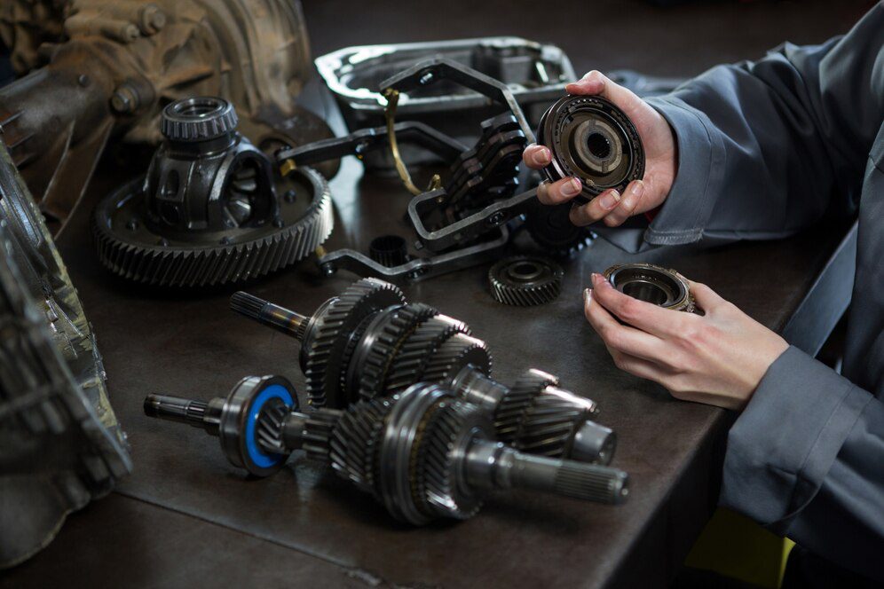 Female mechanic holding spare parts of car<br />
