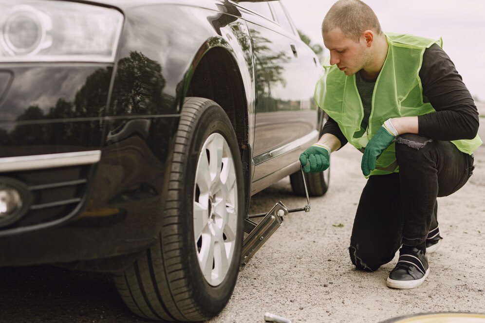 Man changing broken wheel on car<br />
