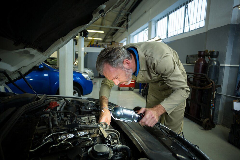 Mechanic examining a car with lamp<br />
